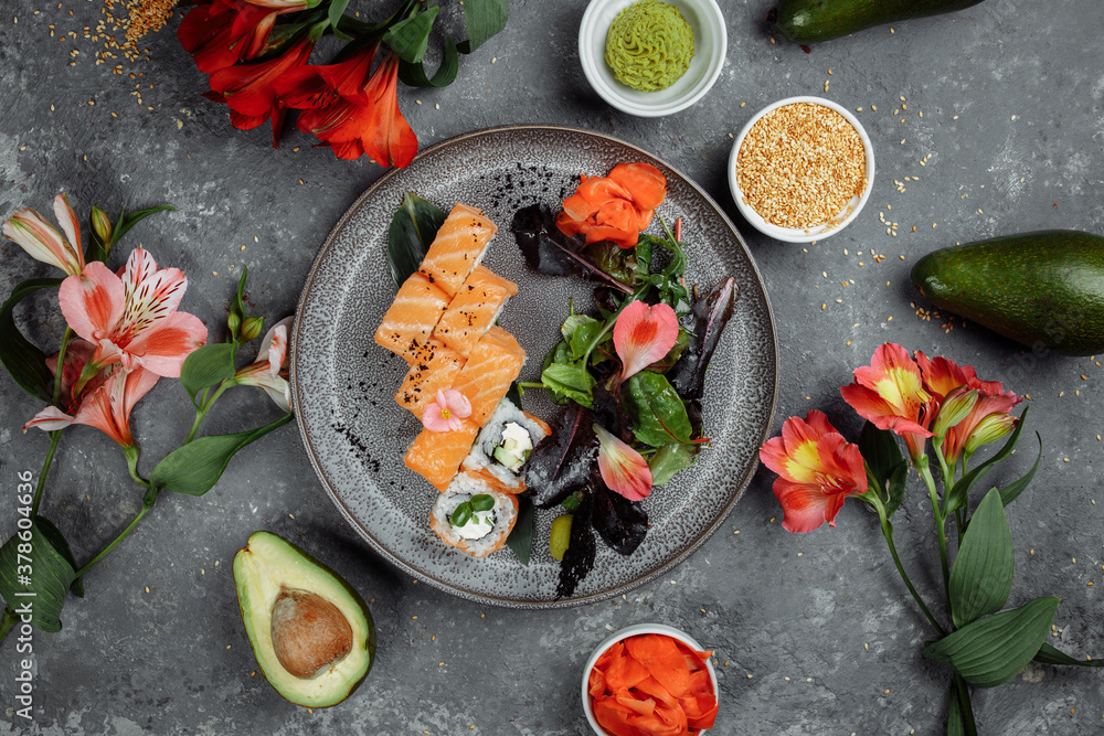 Delicious fresh sushi rolls with salmon and philadelphia cheese on gray plate on dark stone background. Traditional japanese seafood, healthy food concept