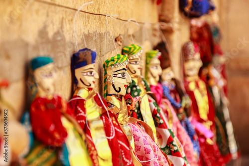 Colorful human face shaped Puppets wearing colorful clothes hanging against the wall in Rajasthan India on 21 February 2018