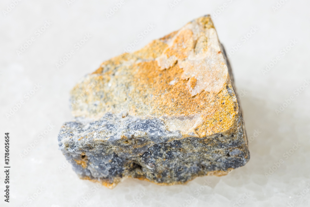 closeup of sample of natural mineral from geological collection - rough Corundum rock on white marble background closeup of sample of natural mineral from geological collection - rough Corundum rock on white marble background
