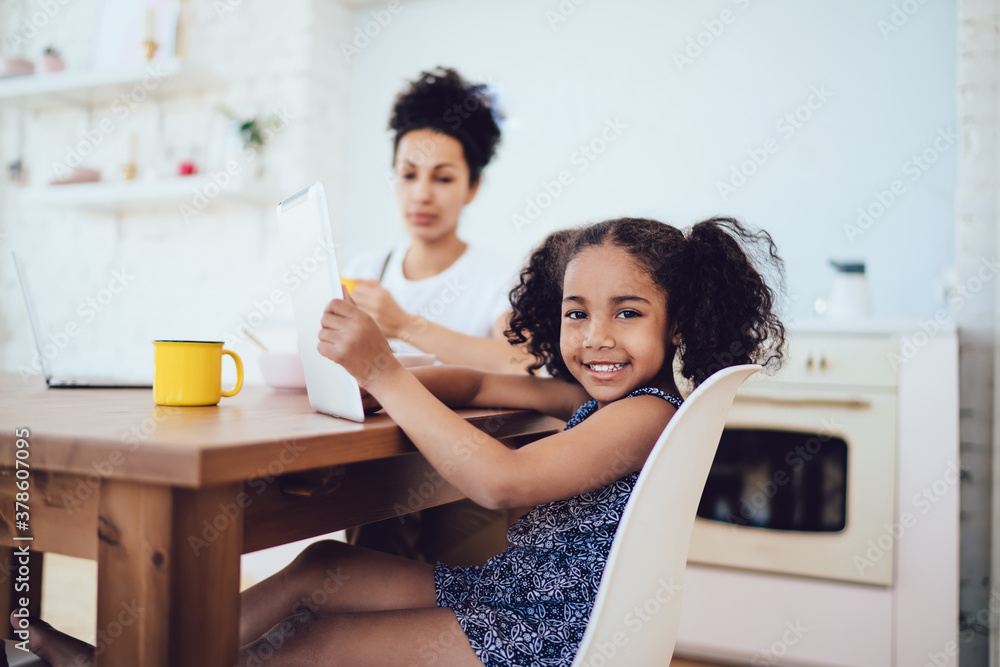Cheerful cute little girl using tablet with young mother at home Cheerful cute little girl using tablet with young mother at home