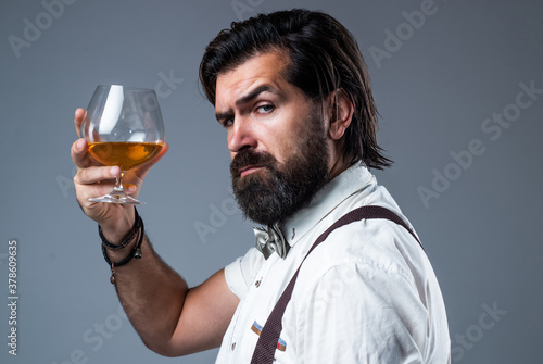 confident bartender male holding scotch glass in hands, drinking alcohol