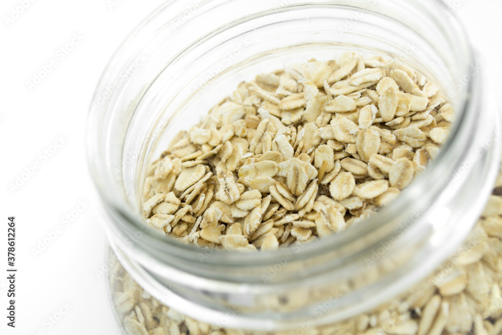 Glass jar full of natural oats, isolated on white background.