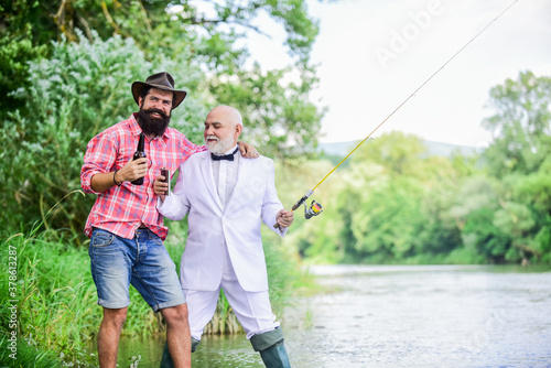 outdoor picnic. summer family weekend. father and son fishing. mature man fisher celebrate retirement. two fishermen with fishing rods. hobby and sport activity. retired businessman. male friendship