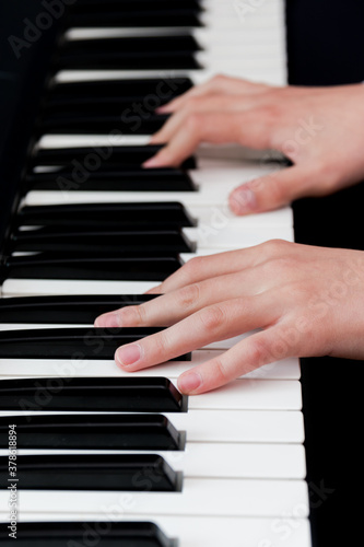 a schoolgirl in a white shirt plays the keys of a synthesizer. selective focus