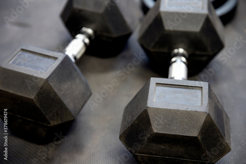 Dumbbells or weights on black rubber flooring tiles inside gym Concept for workout