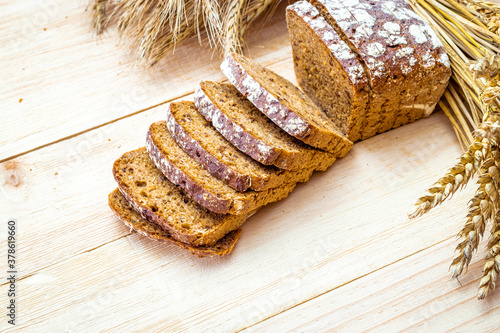 Freshly baked bread. Fresh loaf of rustic traditional bread with wheat grain ear or spike plant on wooden texture background. Rye bakery with crusty loaves and crumbs. Healthy Food concept.