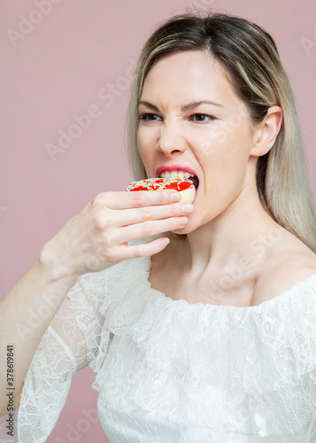 beautiful girl playing with donuts on a pink background. Diet, dieting concept. Junk food, weight loss