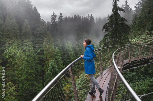 Canada Autumn travel destination in British Columbia. Asian tourist woman walking in famous attraction Capilano Suspension Bridge Park in North Vancouver, canadian vacation for tourism. photo