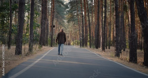 Drunk homeless man walks on the road in the park photo