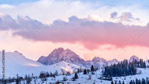 Fototapeta Naklejka Na Ścianę i Meble -  Sunset with dramatic sky and snowy mountain peaks illuminated by sunlight, Tatra Mountains in winter time. Mountain range in Bialka Tatrzanska, Poland