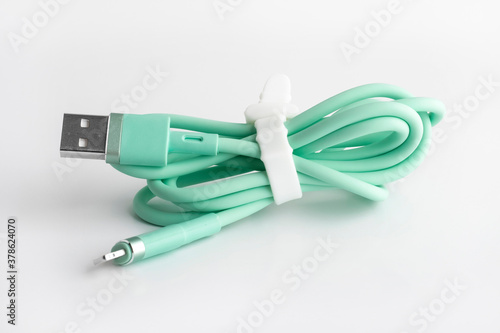 Green usb cable for charging a mobile phone on a white background. silicone mobile phone accessory