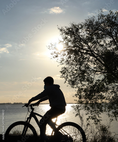 bicycle rider silhouette in front of the lake