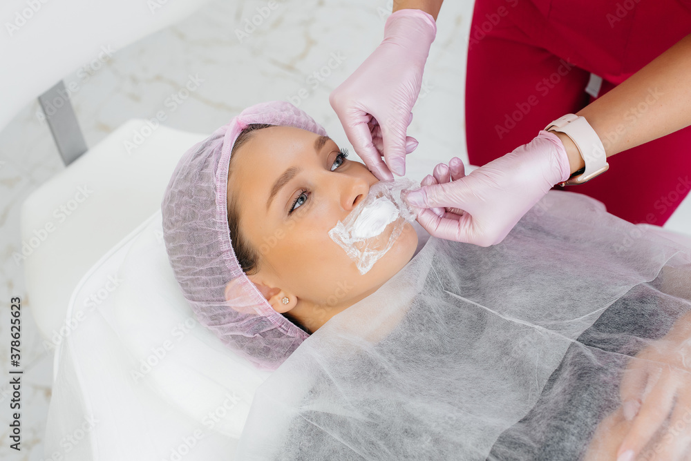 Moisturizing the lips during a cosmetic procedure for a young girl. Cosmetology
