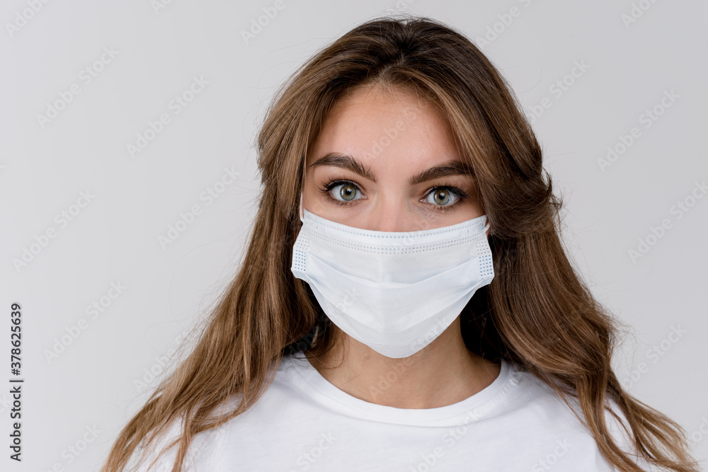 Studio portrait of young woman wearing a face mask, looking at camera, close up, isolated on gray background Studio portrait of young woman wearing a face mask, looking at camera, close up, isolated on gray background