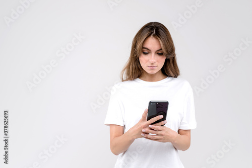 Woman wearing a white shirt using a mobile phone isolated on a white background © Iryna