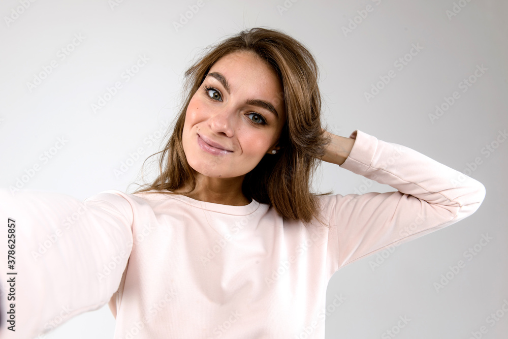 Close-up portrait of a young beautiful woman taking selfie isolated on white background Close-up portrait of a young beautiful woman taking selfie isolated on white background