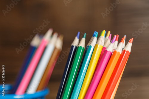 Pens and pencils in metal holder in front of wall background