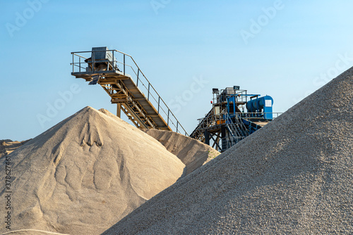 Schilderij op canvas Conveyor belt over heaps of gravel against the blue sky at an industrial cement plant