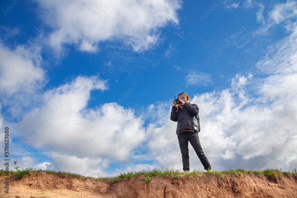 a tourist girl with a backpack and a camera walks along the river Bank on a Sunny day, taking pictures of the landscape, autumn a tourist girl with a backpack and a camera walks along the river Bank on a Sunny day, taking pictures of the landscape, autumn