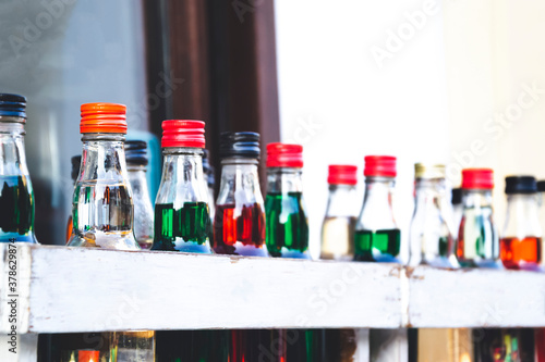 Close up picture of small bottles with colorful caps on the top. Range shades of drinks. Group of colorful little liquor bottles in the restaurant. Copy space for text and background. 