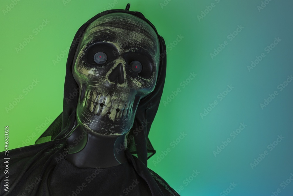 Close up view of black lighted skeleton figure on green-blue background. Halloween concept. Close up view of black lighted skeleton figure on green-blue background. Halloween concept.