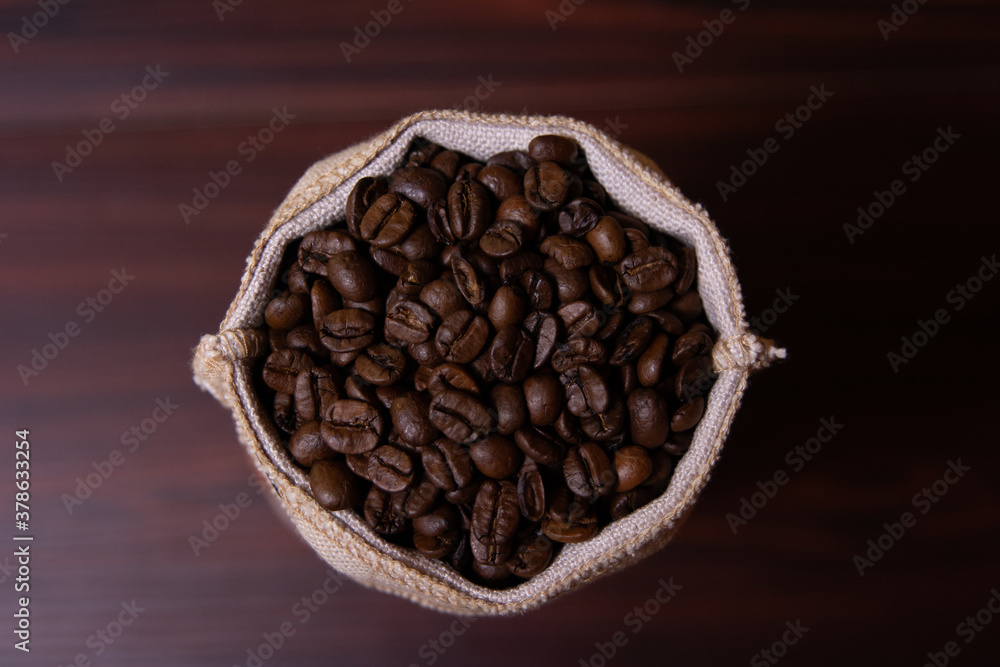 Fototapeta premium Kaffeebohnen in einem Leinenbeutel von Oben auf dunklem Tisch