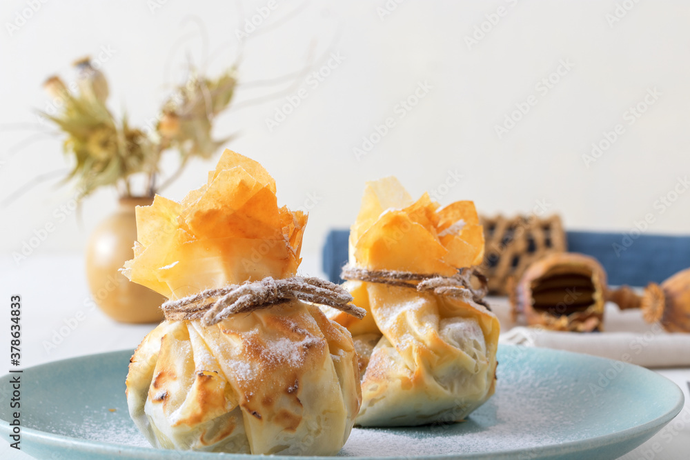 Plum and poppy seeds phyllo purses on a white wooden, delicious vegetarian dessert on a white wooden table. Plum and poppy seeds phyllo purses on a white wooden, delicious vegetarian dessert on a white wooden table.