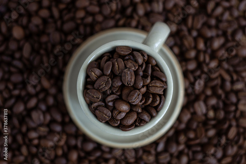 Coffee beans in brown coffee cup and coffee beans in the background