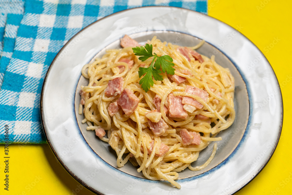 creamy spaghetti pasta with ham on yellow background