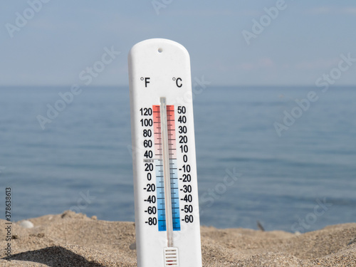 a thermometer in the hot sand on the beach showing about about 86 degrees Fahrenheit 30 Celsius