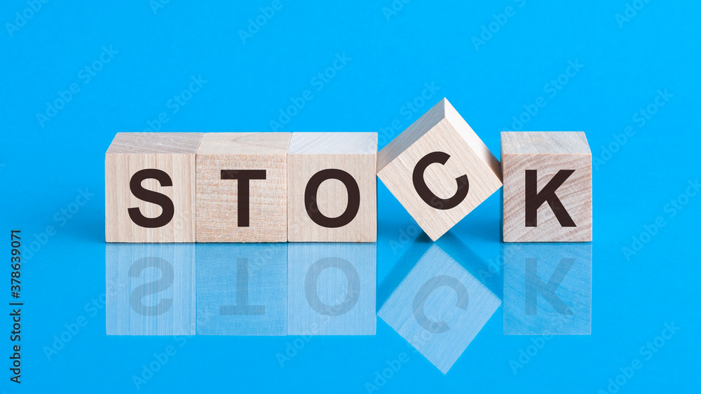 The text STOCK is written on the cubes in black letters, the cubes are located on a blue glass surface. The text STOCK is written on the cubes in black letters, the cubes are located on a blue glass surface.