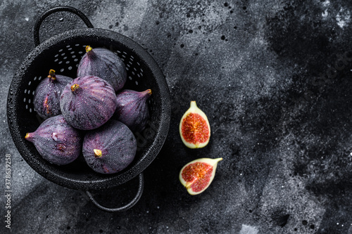 Figs in a colander, organic fruit. Black background. Top view. Copy space