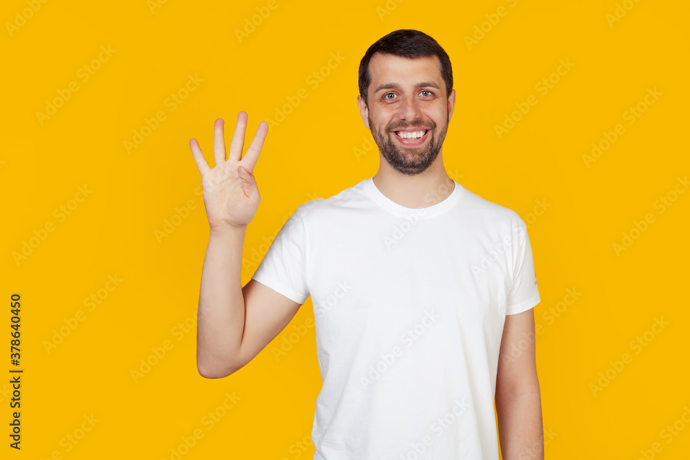 Modern young man with a beard in a white tank top shows number four with fingers on hand, smiling confidently and happily, looking at the camera. The man shows four fingers. Number 4 yellow background Modern young man with a beard in a white tank top shows number four with fingers on hand, smiling confidently and happily, looking at the camera. The man shows four fingers. Number 4 yellow background