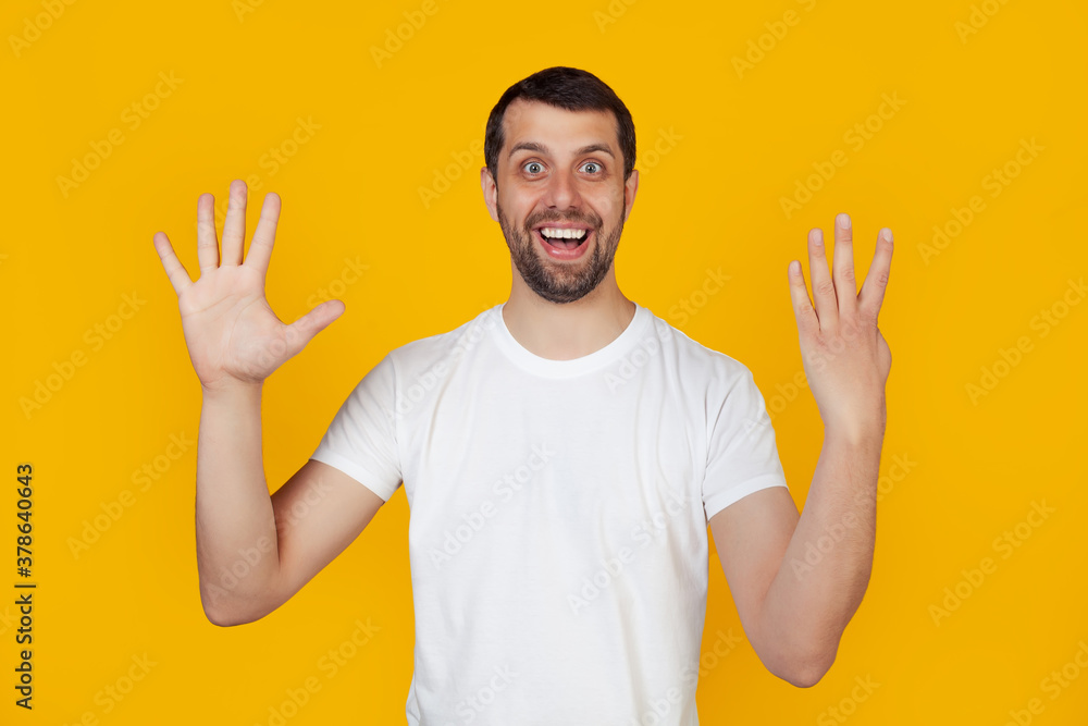 Modern young man with a beard in a white tank top shows number nine with fingers on hand smiling confidently and happily looking into the camera. The man shows nine fingers. Number 9 yellow background Modern young man with a beard in a white tank top shows number nine with fingers on hand smiling confidently and happily looking into the camera. The man shows nine fingers. Number 9 yellow background