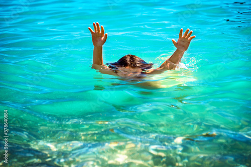 Close up two kid s hands coming out of the blue green water. Sunny summer day