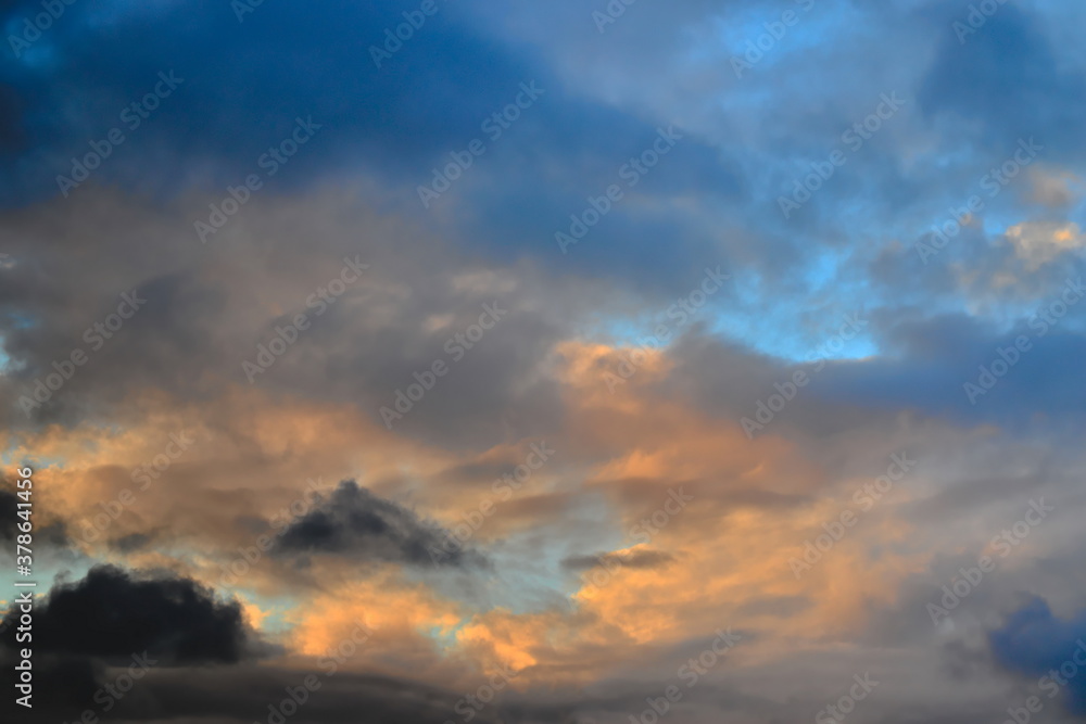 tufts of clouds shaded with gray and orange covering a twilight blue sky.