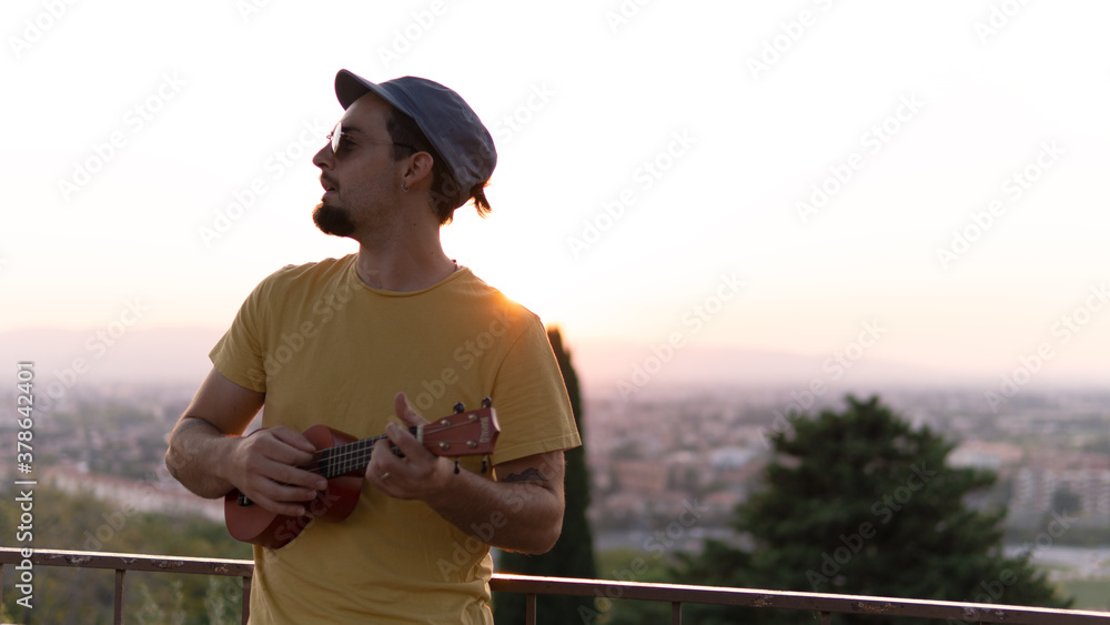A boy playing the ukulele and the city in the background. A boy playing the ukulele and the city in the background.