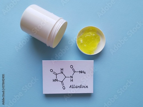 Structural chemical formula of allantoin molecule with comfrey gel in plastic jar. Allantoin is present in botanical extracts of the comfrey plants, stimulates tissue repair and wound healing. photo