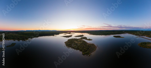 Picturesque Aerial View of Canadian Scenic Island surrounded by Peaceful Lakes. Vibrant summer sunset on the horizon. Cariboo Highway, Interior British Columbia.