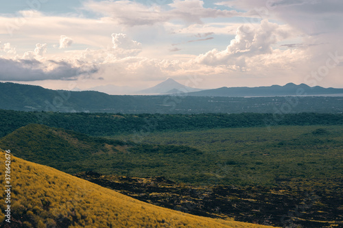 Fototapeta Naklejka Na Ścianę i Meble -  Wonderful view of Momotombo volcano from the top of Masaya volcano national park with a hill covered by grass on the foreground