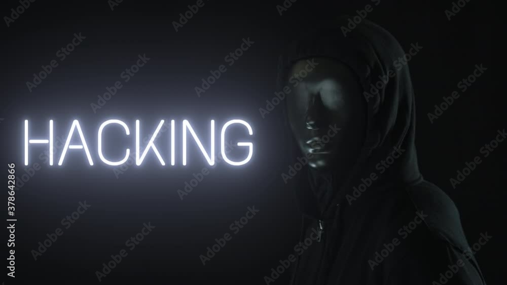 Man wearing black mask and the light revealing HACKING word Man wearing black mask and the light revealing HACKING word