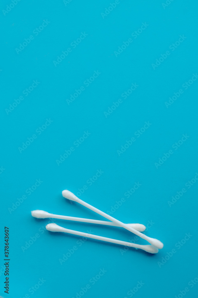 Cotton ear swabs sticks on blue background. close up. Image with selective focus, noise effect and toning. Top view. Flat lay. Cotton ear swabs sticks on blue background. close up. Image with selective focus, noise effect and toning. Top view. Flat lay.