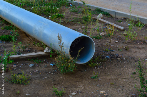 Wallpaper Mural a large gray metal pipe with a hole lies on the wet ground in the city. construction site, water drainage system. sewerage production. water drains underground Torontodigital.ca