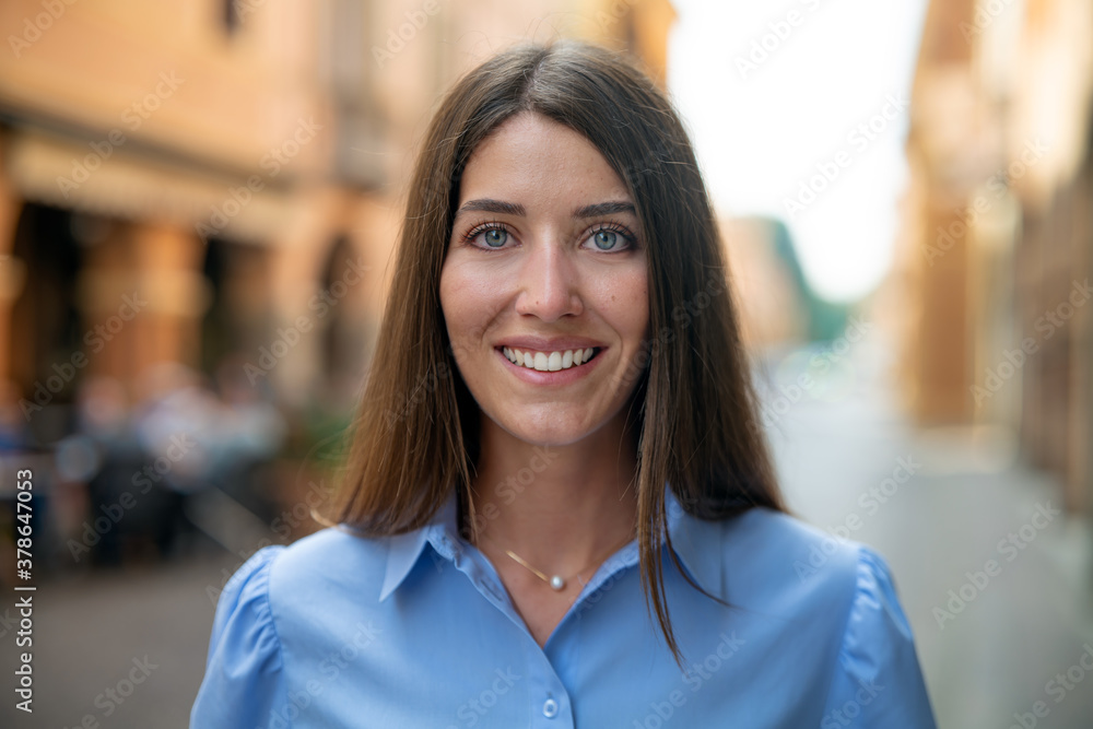 Authentic shot of an young carefree happy woman is smiling in camera in old city center on a sunny day. Authentic shot of an young carefree happy woman is smiling in camera in old city center on a sunny day.