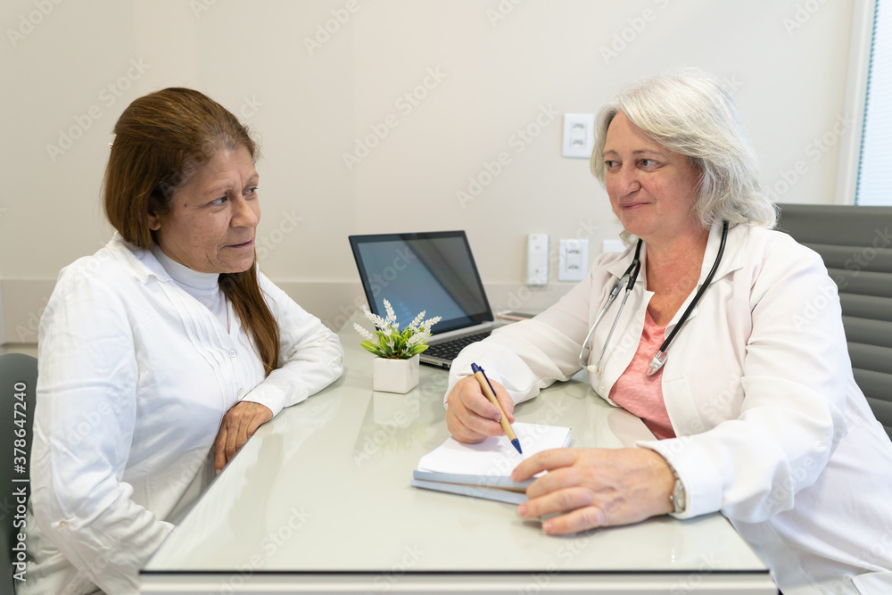 Friendly elderly female doctor with stethoscope talking to patient at medical clinic healthcare, clinic, treatment concept.. Friendly elderly female doctor with stethoscope talking to patient at medical clinic healthcare, clinic, treatment concept..