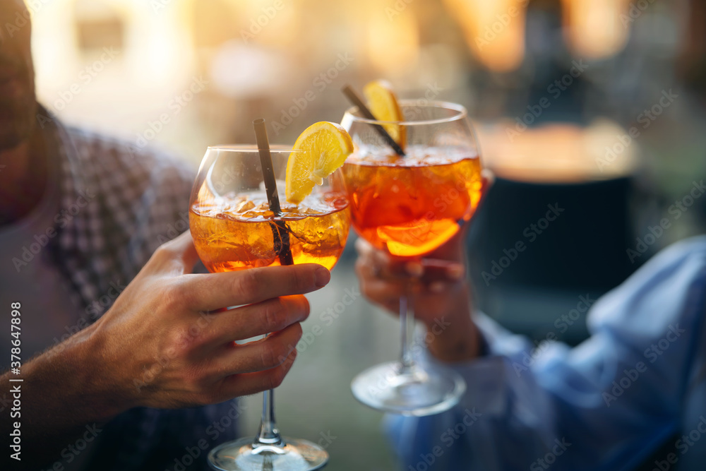 Close up shot of an young carefree romantic couple in love is drinking and cheering with cool alcohol cocktails while enjoying a happy hour time together in city center bar on a weekend in a sunny day