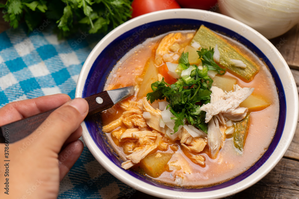 Mexican chicken soup with vegetables and rice on wooden background Mexican chicken soup with vegetables and rice on wooden background