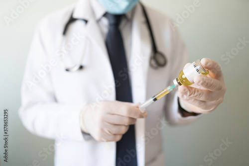 Doctor holding a syringe and vaccine in a studio