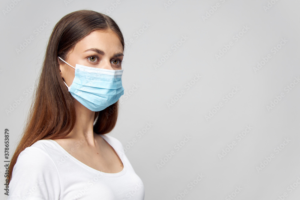 Woman in a white T-shirt and in a medical mask on an isolated background Woman in a white T-shirt and in a medical mask on an isolated background