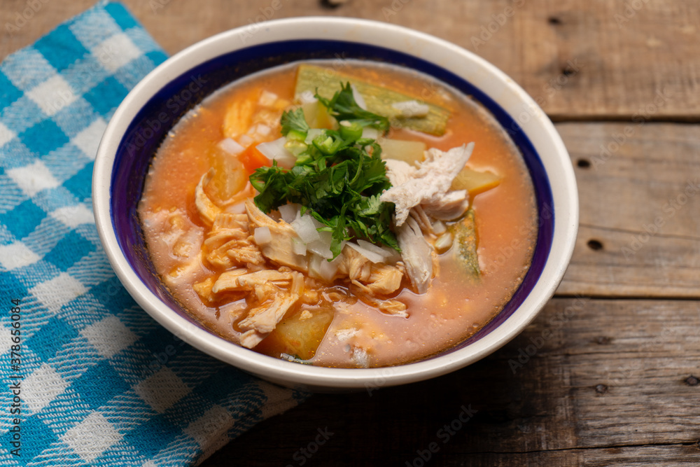 Mexican chicken soup with vegetables and rice on wooden background Mexican chicken soup with vegetables and rice on wooden background